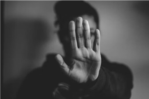 uma pessoa colocando a mão na frente para esconder o seu rosto